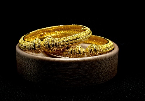 A pair of gold bangles jewelry isolated on dark background