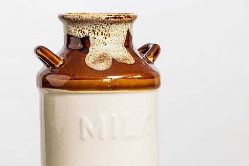 A closeup of a ceramic milk jug on a white background