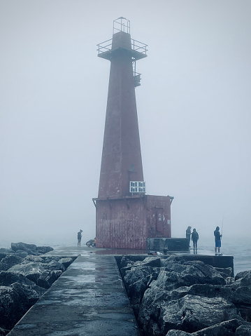 A group of fishermen near Muskegon South Pierhead Lighthouse in Michigan, USA on a foggy day