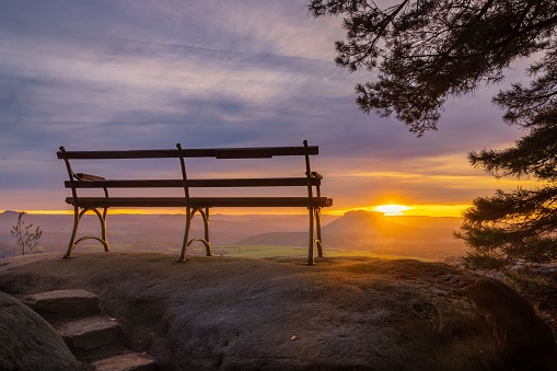 A scenic view of an empty bench on a hill at sunset in the Saxon Switzerland National Park, Germany