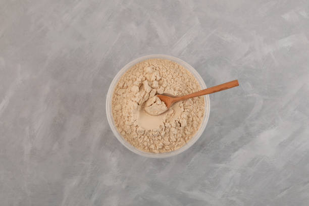 istock Soy Protein isolate in plastic container, top view. Pure powder  isolated from soybean. Soy protein isolate is often used in meat industry in production of minced meat and sausages 1464403516