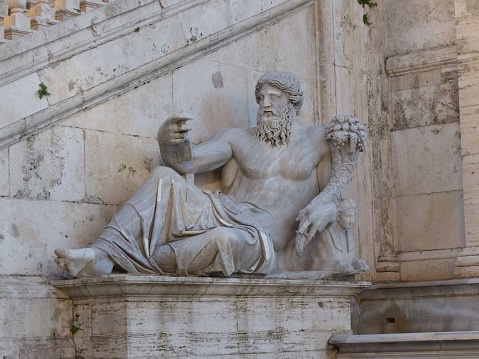 An ancient roman statue of the God Zeus by the Tiber river in Rome, Italy