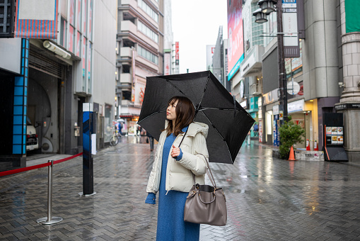 Woman walking in city in a rainy day