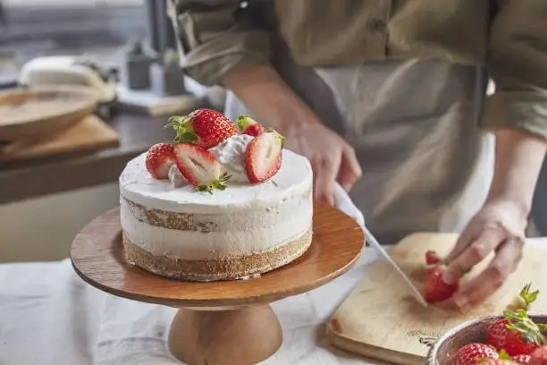A closeup of a baker preparing a delicious strawberry cake