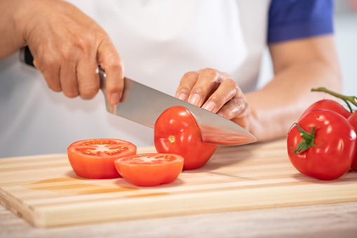 female hands cutting tomato on a wooden cutting board: Selective focus. Diet and healthy food concept