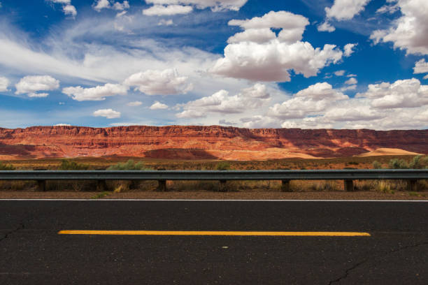 autostrada attraverso i deserti sotto il cielo nuvoloso - arid climate asphalt barren blue foto e immagini stock