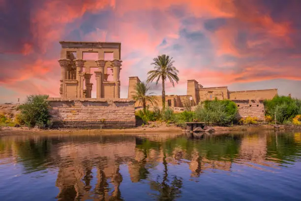 the orange sunrise at the temple of Philae seen from the Nile river