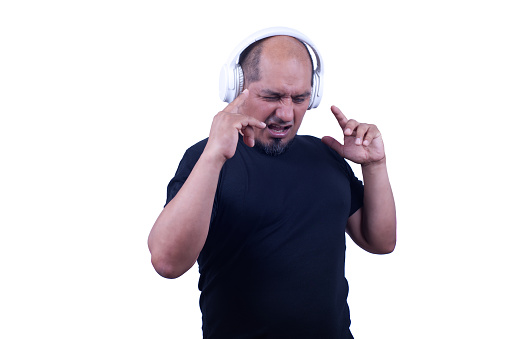 Man on a white background, moves his hands to the rhythm of the music he is listening to in his white headphones.