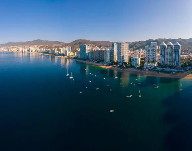 An aerial view of the Acapulco Bay with boats sailing on the calm dark blue water under the scorching sun