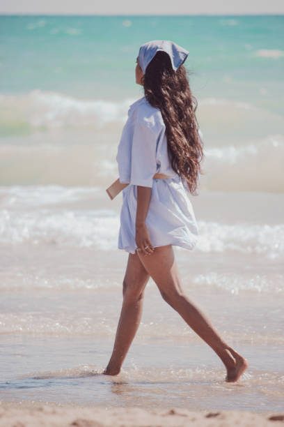 istock Young female strolling along the beach and enjoying a sunny day 1464417526