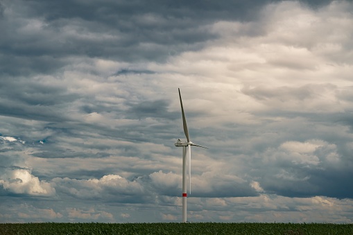 A closeup shot of a windmill in the field under a cloudy sky