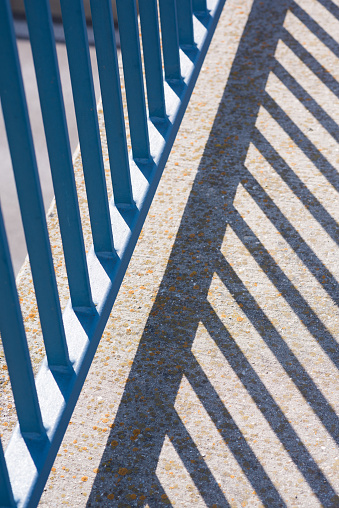 Blue railing, rods with shadow in summer light