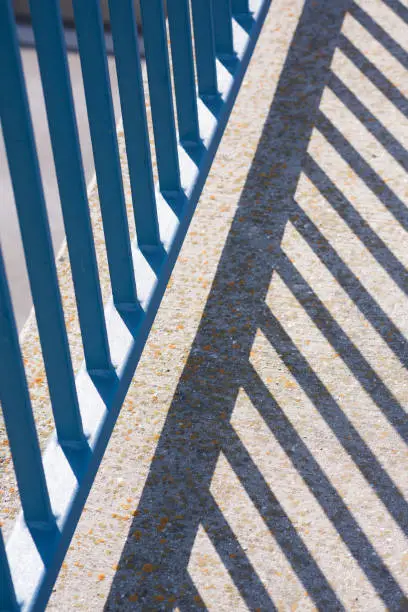Photo of Blue railing, rods with shadow