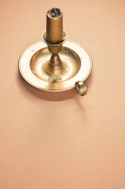 A candleholder with gold candle isolated on orange background with free space for text