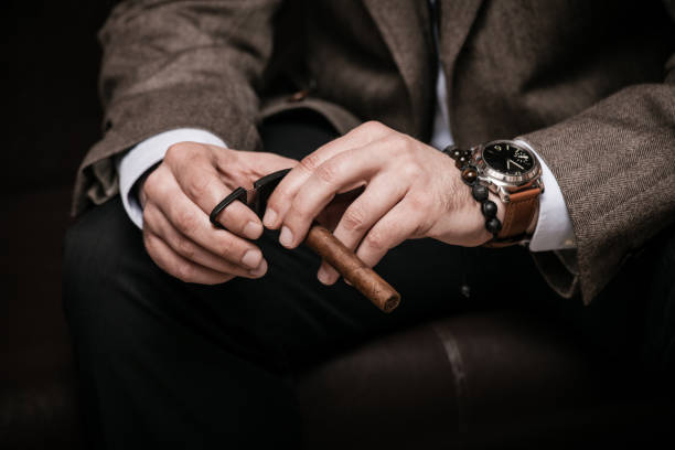 elegant man wearing suit and white shirt cut Cuban cigar elegant man wearing suit and white shirt cut Cuban cigar indoor shot, closeup, selective focus man cigar stock pictures, royalty-free photos & images
