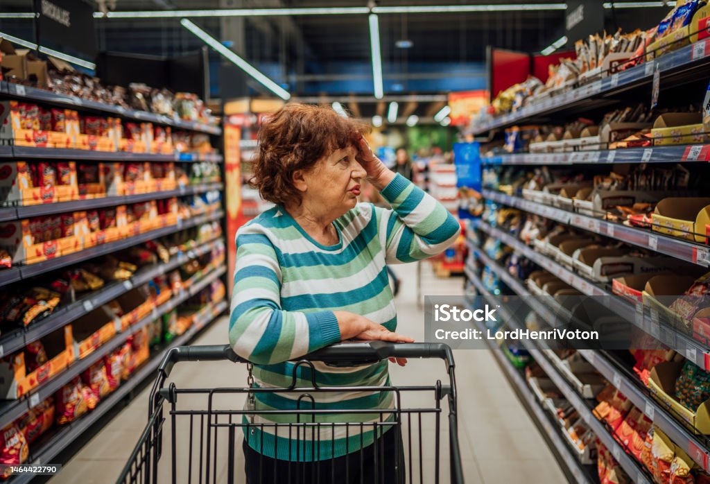 Senior woman feeling shocked about rising grocery prices Senior woman feeling shocked about rising grocery prices in the supermarket Supermarket Stock Photo