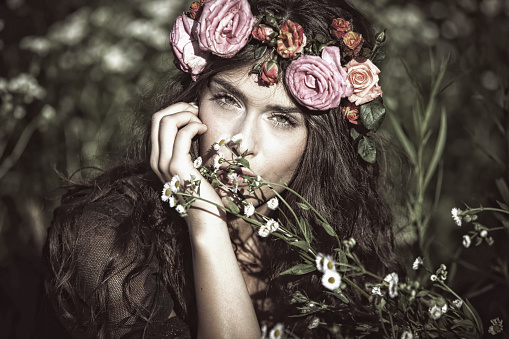 young beautiful woman portrait with wreath of flowers in field summer day