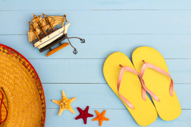 istock Cool view on painted light blue wood table with flip flops, sailboat, hat, and starfish 1464427468