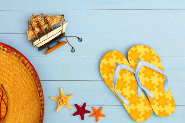 istock Cool view on painted light blue wood table with flip flops, sailboat, hat, and starfish 1464427470