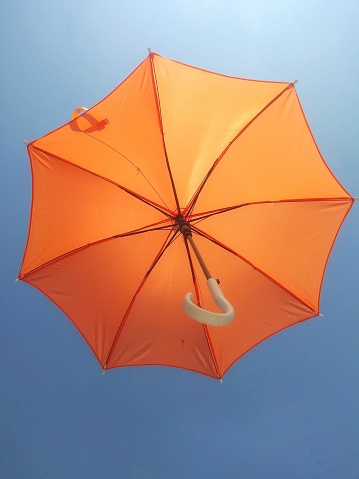 Flying orange umbrella with bluesky background. Great for background and other purposes.