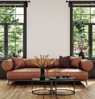 Cozy, luxurious, and empty modern living room with two beige textile sofas, a cozy chair, and decoration (pillows, blankets) on the hardwood floor in front of a blank red plaster wall background with copy space. A low coffee table in front of the sofa with decorations, glasses, coffee cups, and a vase of flowers. Large sliding windows with a terrace and garden view (chairs, tables, and trees) on both sides of the room. An aluminum modern staircase leads to the upper floor in the background. A slight vintage effect was added. 3D rendered image.