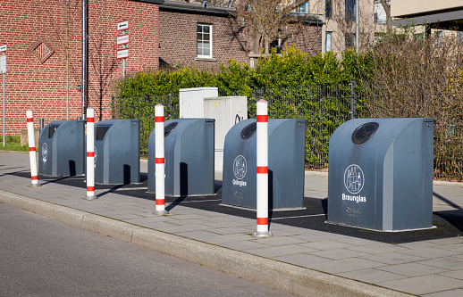 Row of 5 gray recycling containers for glass and paper, Germany.
