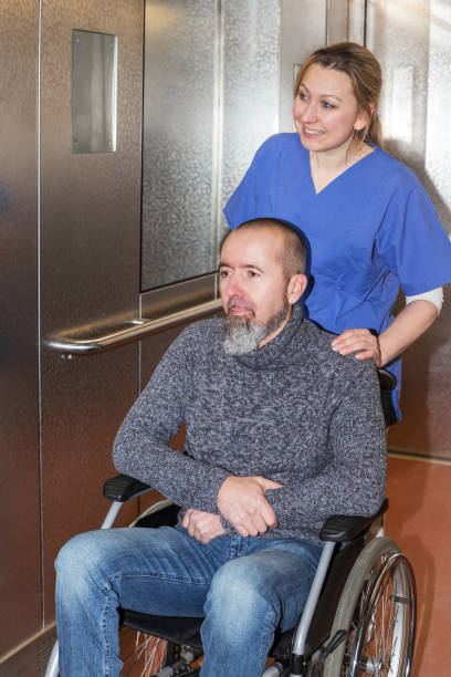 istock patient in wheelchair and nurse in elevator 1464434284