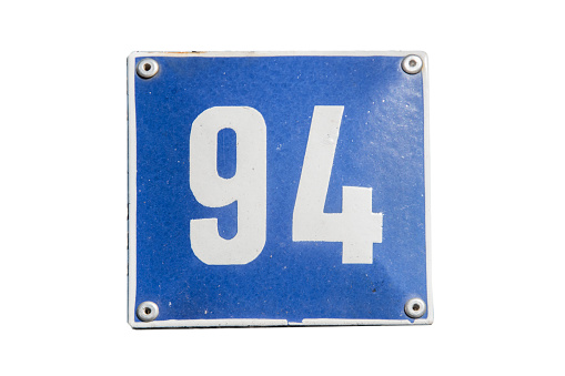 Weathered grunge square metal enameled plate of number of street address with number 94 closeup isolated on white background
