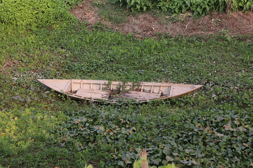 A broken boat is staying in the side of the pond from Bangladesh