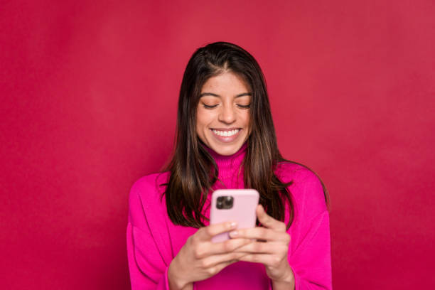 Smiling woman using smartphone against red background