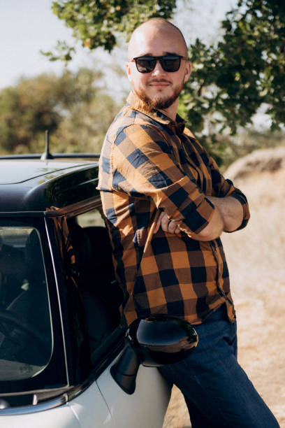 istock Guy in a plaid shirt next to a white car 1464442255