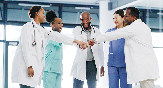Trabajo en equipo en grupo médico, las personas golpean el puño en el hospital con médicos y enfermeras sonriendo juntos. Los orgullosos profesionales de la salud celebran el éxito, los empleados en la fuerza laboral y la solidaridad del personal photo