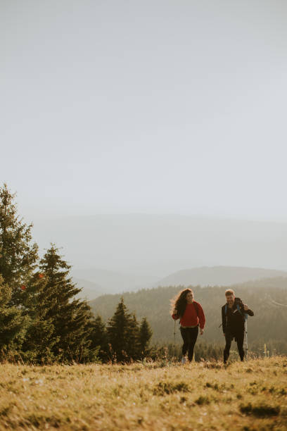 istock Smiling couple walking with backpacks over green hills 1464442966