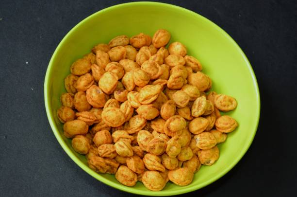 istock Roasted crushed peanuts. Peanuts coated with gram batter with different spices and roasted. Delicious snacks served in a green coloured bowl with black background. 1464456478