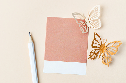 Blank reminder note and carve of paper butterfly with pencil on yellow background, space for text.