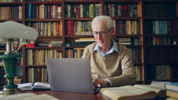 istock Senior man scientist typing on laptop, working on research at library, enjoying his day 1464459368