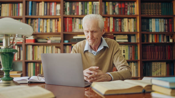 istock Overworked mature man looking at laptop display, sitting at library, reading his work 1464459389