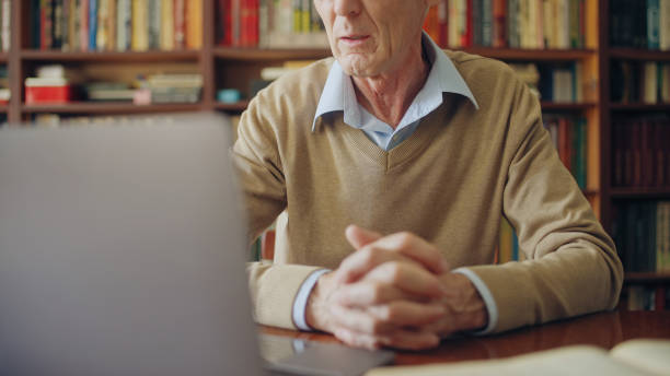 istock Senior university professor teaching lecture on laptop, sitting at the library 1464459444
