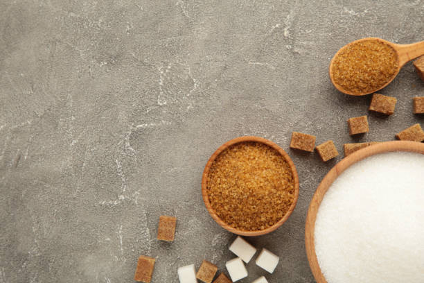 istock White and brown sugar in bowl on grey background. 1464459459