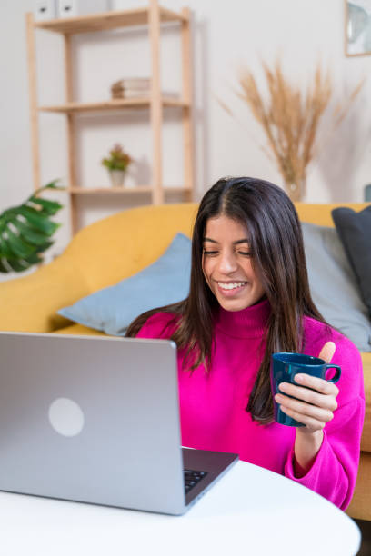 istock Smiling ethnic woman with cup of coffee using laptop 1464459514