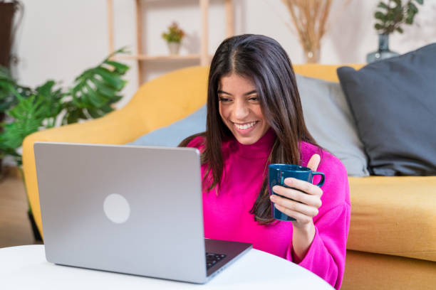 istock Smiling ethnic woman with cup of coffee using laptop 1464459612