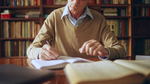 istock Senior male writer taking short notes in notepad, studying literature in a library 1464459784