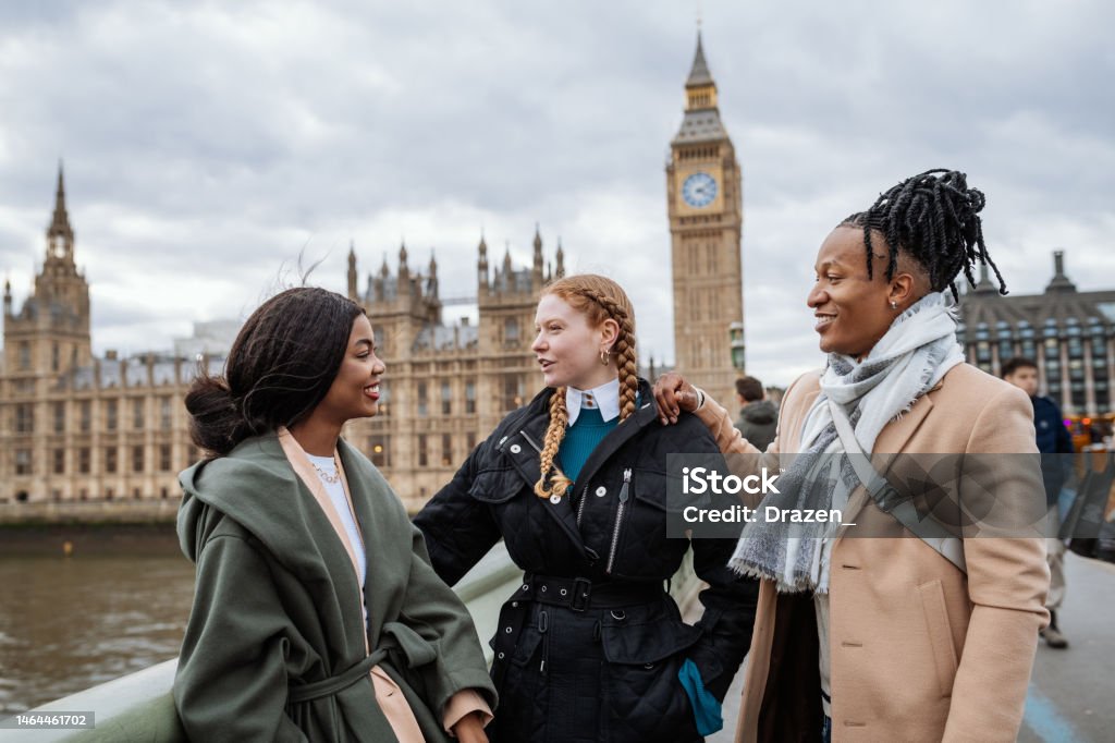 British youth in wintertime, outdoors, standing near Big Ben and talking Young multi-ethnic tourists in London,UK during wintertime London - England Stock Photo