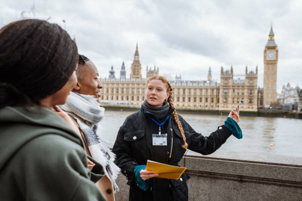 Young tourists in London, followed by private tour guide, showing them Parliament and Big Ben stock photo