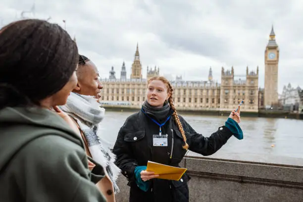 Photo of Young tourists in London, followed by private tour guide, showing them Parliament and Big Ben