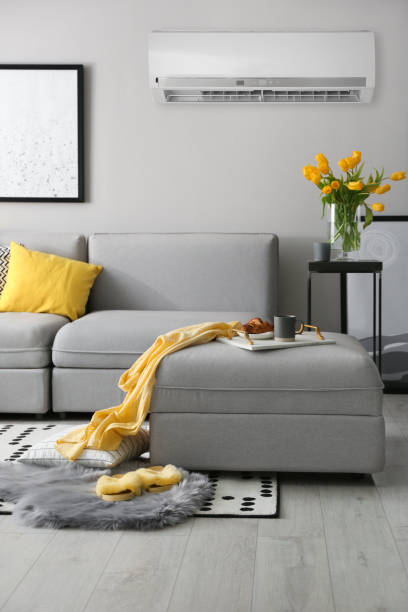 istock Modern air conditioner on light grey wall in living room with stylish sofa 1464461938