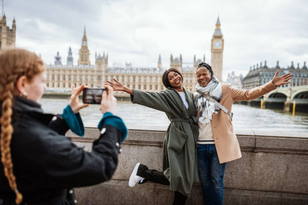 young african couple are tourist in london, in wintertime. redhead woman taking pictures with smart phone - women travel destinations london england tourist imagens e fotografias de stock