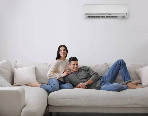 istock Happy couple resting under air conditioner on white wall at home 1464462108