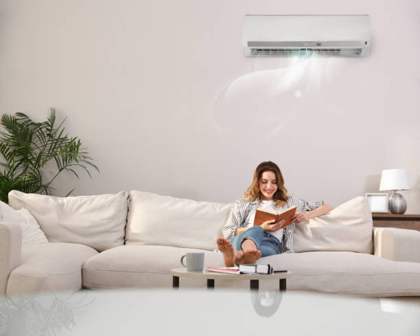istock Young woman resting under air conditioner on white wall at home 1464462111