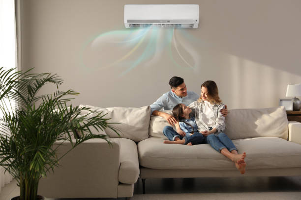 Happy family resting under air conditioner on beige wall at home stock photo